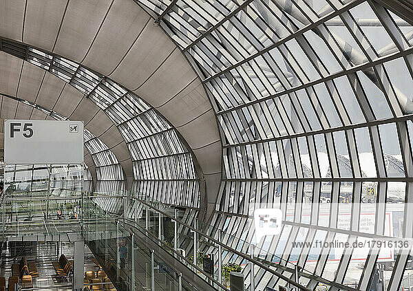 Abflug-Gate am Flughafen Bangkok  ein Blick von oben auf eine gebogene Glaswand des Terminals und den Wartebereich.