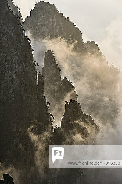 Die steilen  zerklüfteten Granitgipfel des Huangshan-Gebirges  die Gelben Berge  Nebel und Wolken in den Tälern zwischen den Gipfeln.