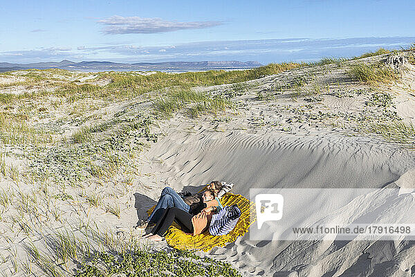 Mother and teen daughter (16-17) lying on sand dunes on Grotto Beach