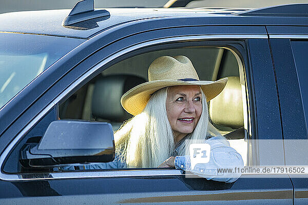 Senior woman in car wearing cowboy hat