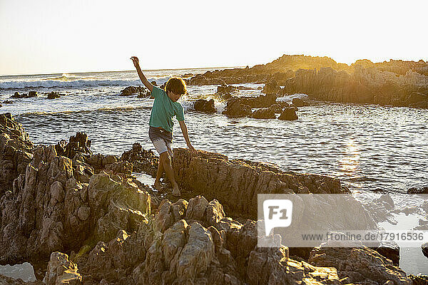 South Africa  Gansbaai  De Kelders  Boy (8-9) exploring rocky coastline
