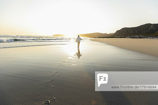 South Africa  Hermanus  Teenage girl (16-17) walking on Grotto Beach at sunset