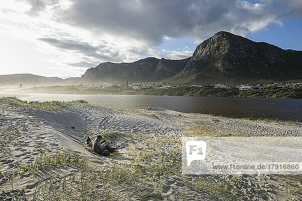 South Africa  Hermanus  Mother and teen daughter (16-17) lying on sand dunes on Grotto Beach