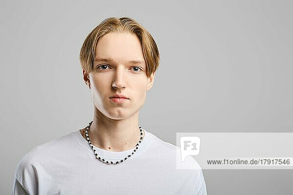 Closeup Porträt von ernsten jungen Mann in weißem T-Shirt über grauem Hintergrund Studio