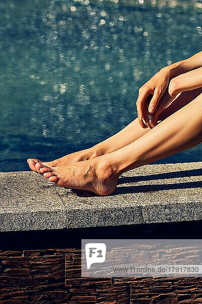 Weibliche Beine und Hände unter der Sonne in der Nähe des Wassers in schwülen heißen Tag