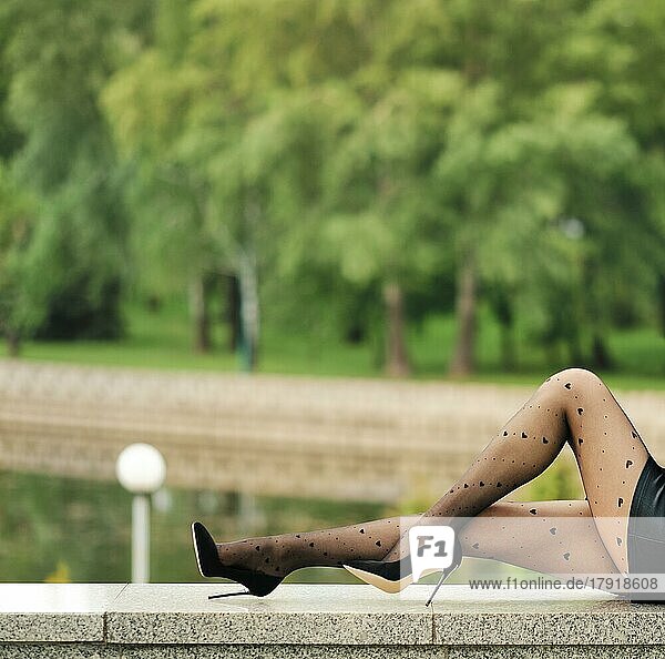 Schlanke Frauenbeine in Strumpfhose mit Herzmuster im Profil mit Stadtpark im Hintergrund