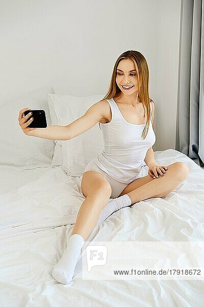 Junge Frau macht Selfie für soziales Netzwerk im Bett