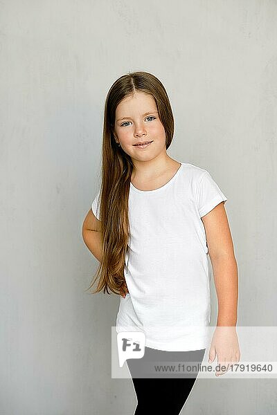 Cute young child with long hair in white t-shirt and black sweatpants posing