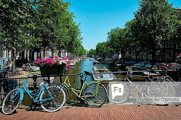 AMSTERDAM  NIEDERLANDE  21. MAI 2018: Typische Ansicht von Amsterdam  Amsterdamer Gracht mit Booten und Fahrrädern auf einer Brücke mit Blumen. Amsterdam  Niederlande  Europa