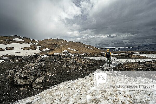 Wanderer in schneebedeckter Vulkanlandschaft mit vulkanischem Sand und versteinerter Lava  Krater des Vulkans Askja  isländisches Hochland  Island  Europa