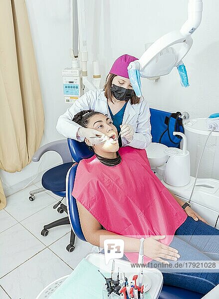 Zahnarzt in seinem Büro untersucht den Mund einer Patientin. Weiblicher Zahnarzt untersucht den Mund von Teenager-Mädchen  die auf dem Stuhl liegen  Weiblicher Zahnarzt mit Sonde und Zahnspiegel  der den Mund einer jungen Frau untersucht