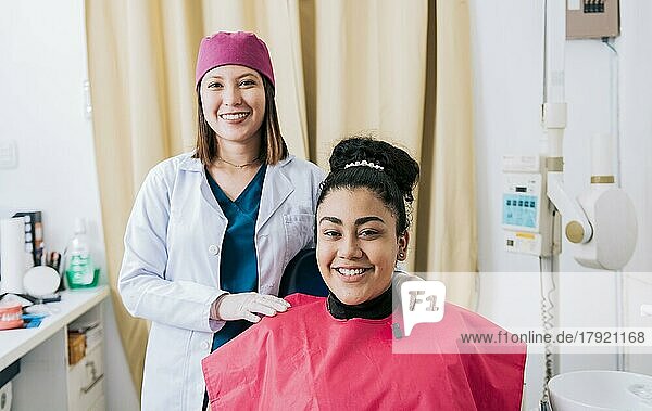Weiblicher Zahnarzt mit zufriedenen Patienten lächelnd in die Kamera  Weiblicher Zahnarzt mit Patienten lächelnd freundlich. Porträt des Zahnarztes mit Patient lächelnd in die Kamera im Büro