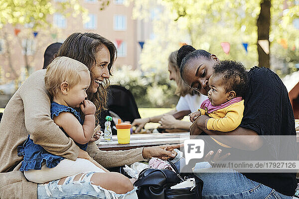 Mütter spielen mit Töchtern  die im Park sitzen