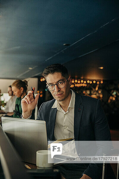 Porträt eines Geschäftsmannes mit Brille  der mit einem Laptop in einem Hotel sitzt