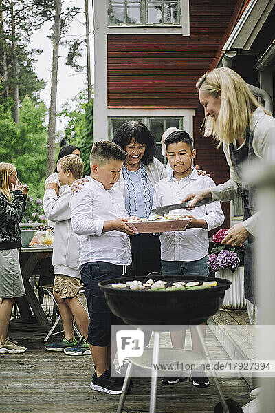 Grandmother with grandchildren taking barbecue food during party