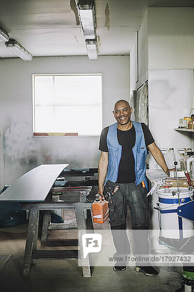 Full length portrait of smiling male painter in workshop