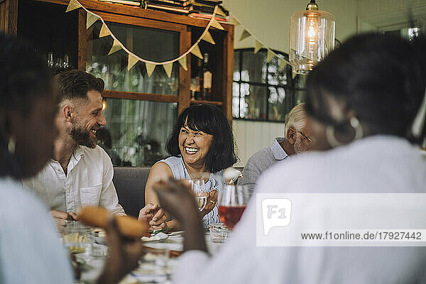 Smiling man looking at woman at dining table during dinner party at home