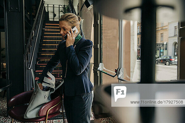 Weibliche Fachkraft  die in einer Hotelhalle mit einem Mobiltelefon spricht