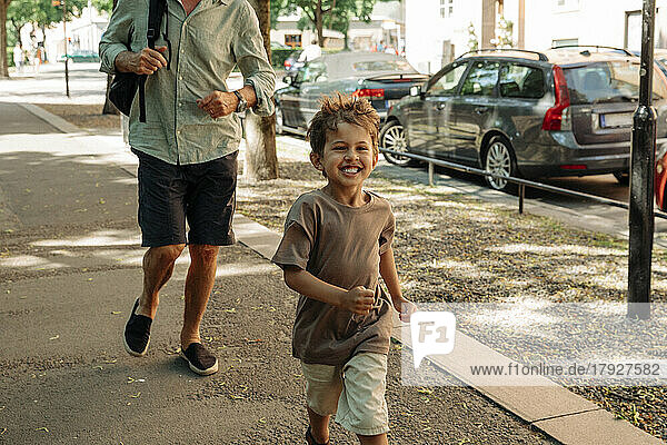 Glücklicher Junge läuft mit Großvater auf dem Bürgersteig