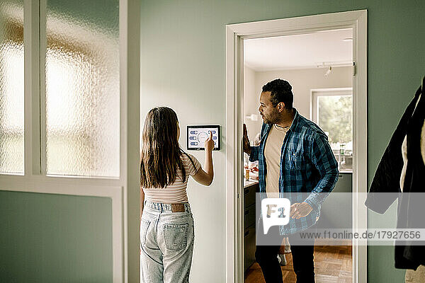 Vater sieht seine Tochter an  die die Heimautomatisierung nutzt  während er an der Tür steht