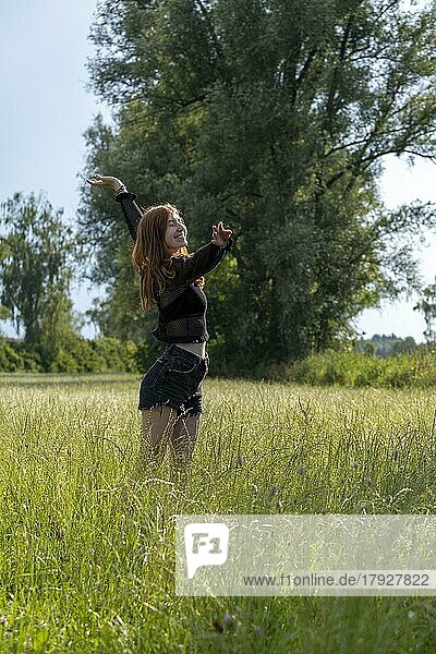 Junge Frau genießt die Natur  im hohen Gras  Naturverbundenheit  Wiese  Landlust  Oberbayern  Bayern  Deutschland  Europa