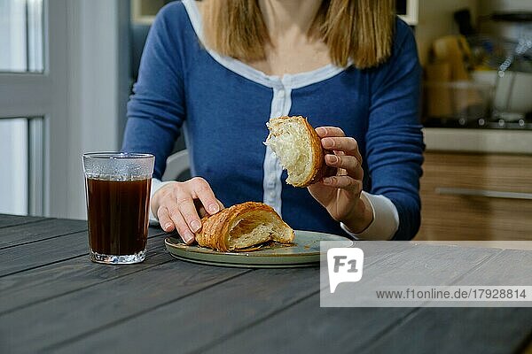 Nahaufnahme von Frauenhänden mit einem Croissant (selektiver Fokus)