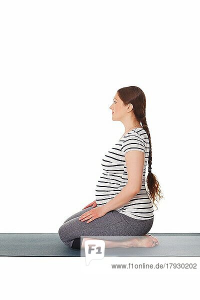 Schwangerschaft Yoga-Übung  schwangere Frau tut Yoga asana Virasana Hero Pose auf Knien vor weißem Hintergrund