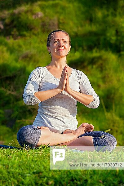 Meditation und Entspannung Yoga im Freien  junge Frau meditiert und entspannt in Padmasana Lotus Pose) mit Kinn Mudra auf grünem Gras im Wald