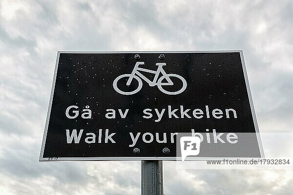 Schwarzweißes Verkehrsschild  zweisprachig mit Piktogramm Fahrrad und Aufschrift Schiebe dein Fahrrad  Radfahrer absteigen  Norwegen  Europa
