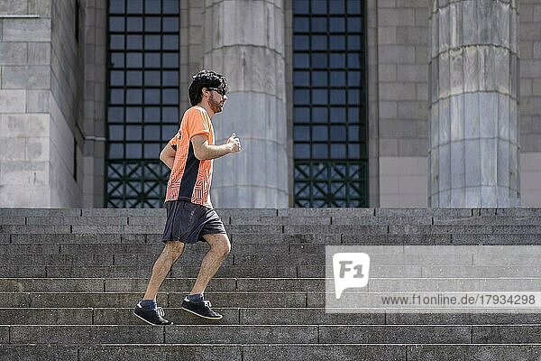 Porträt von gut aussehend attraktiv reifen bärtigen sportlichen lateinischen Mann Kerl 40s in orange T-Shirt läuft auf einigen Treppen