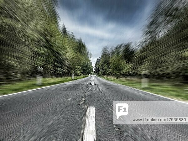 Foto mit Geschwindigkeitseffekt hohe Geschwindigkeit rasen ohne Tempolimit von Landstraße mit Mittelstreifen führt auf lange Gerade geradeaus durch Mischwald bewaldetes Gebiet  Deutschland  Europa