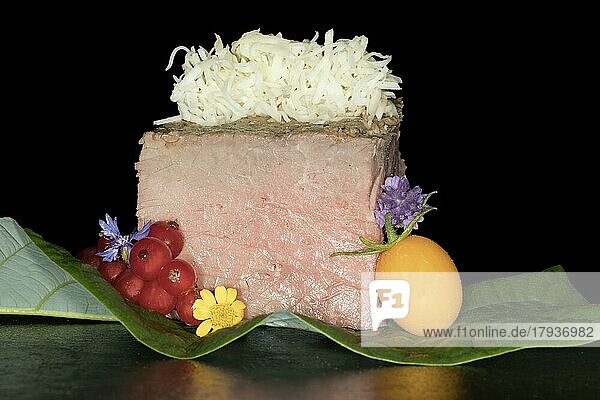 Rosa gebratenes Roastbeef mit frisch geriebenen Meerrettich  Gelbe Kirschtomate  Johannisbeeren und Blüten  Foodfotografie mit schwarzem Hintergrund