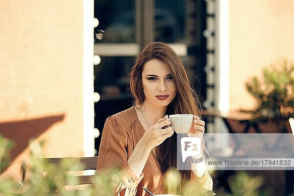 Schöne junge Frau macht Kaffeepause in der Mitte des sonnigen Tages