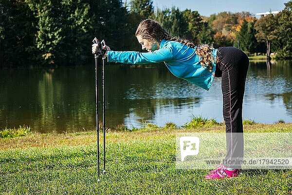 Nordic-Walking-Abenteuer und Trainingskonzept  Frau beim Training mit Nordic-Walking-Stöcken im Park