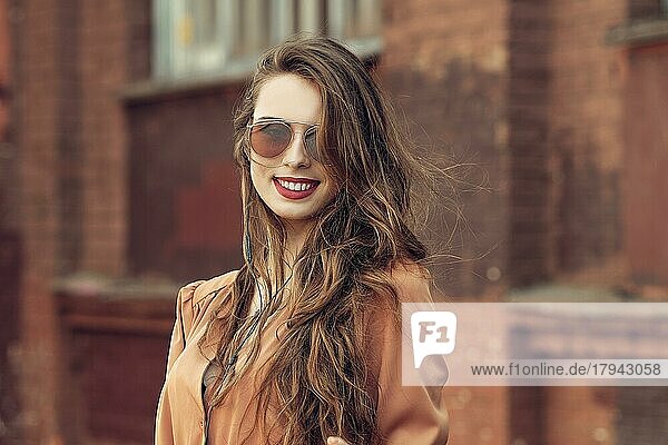 Schöne glückliche junge Frau mit langen lockigen Haaren im Freien