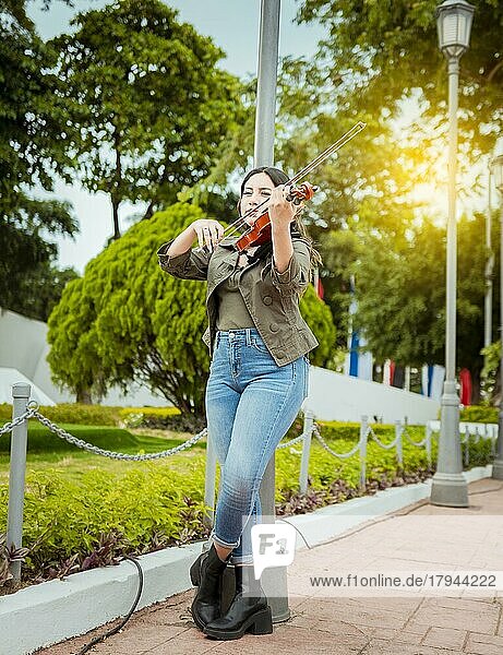 Frau spielt Geige auf der Straße. Porträt von Geigerin Mädchen spielt auf der Straße. Frau Künstlerin spielt Geige im Freien  Mädchen liegt und spielt Geige in einem Park