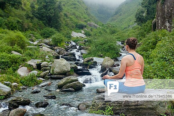 Frau macht Yoga im Freien am Wasserfall