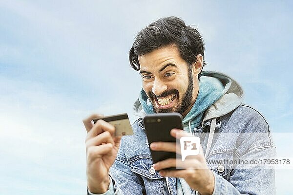 Lateinamerikanischer Mann  der eine Kreditkarte benutzt  um eine Online-Zahlung auf seinem Smartphone vorzunehmen. gemischtrassiger Mann  der sein Mobiltelefon zum Online-Shopping benutzt. Ein Mann benutzt sein Smartphone  um Kreditkartentransaktionen über eine App zu überprüfen. Textfreiraum