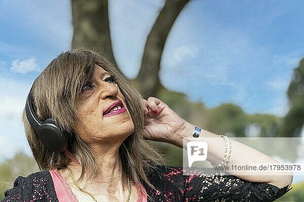 Transfrau hört Musik im Freien mit Kopfhörern. Ausdruck von Glück  gewinnende Haltung. Textfreiraum
