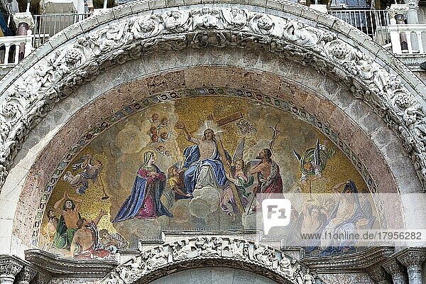 Außenmosaik des Haupteingangs der Kirche. In der Mitte ist Jesus Christus. Auf beiden Seiten zwei klassische Figuren von Fürbittern. Auf der linken Seite die Jungfrau Maria und  in einer typisch venezianischen Interpretation  auf der rechten Seite de...