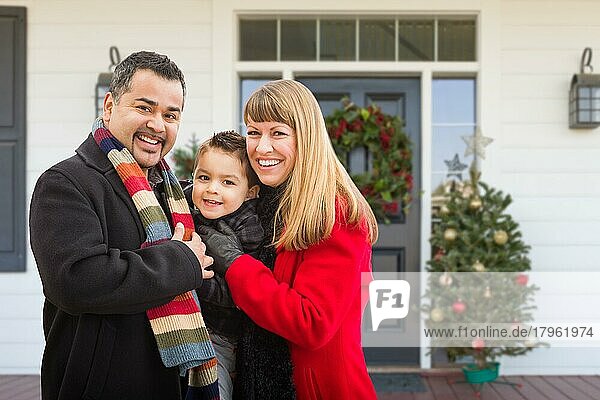 Junge gemischte Familie auf der Veranda eines weihnachtlich geschmückten Hauses