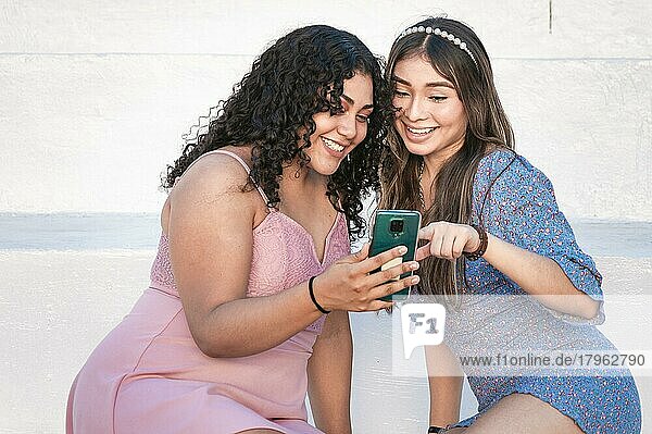 Zwei Mädchen zeigen auf ihr Handy  Mädchen zeigt ihr Smartphone ihrer Freundin  Mädchen überprüft ihr Handy mit ihrer Freundin