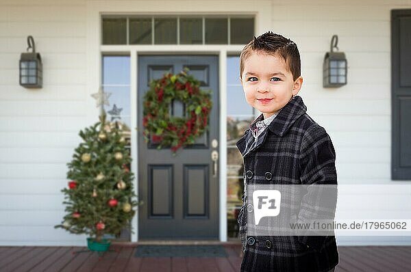 Junger gemischtrassiger Junge auf der Veranda eines Hauses mit Weihnachtsschmuck