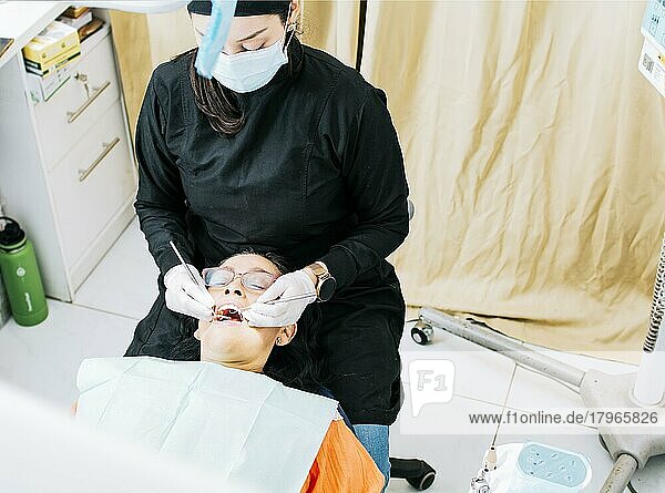 Woman dentist doing endodontics to woman patient  Dentist with patient lying down  Dentist examining mouth to patient  Dentist performing stomatology