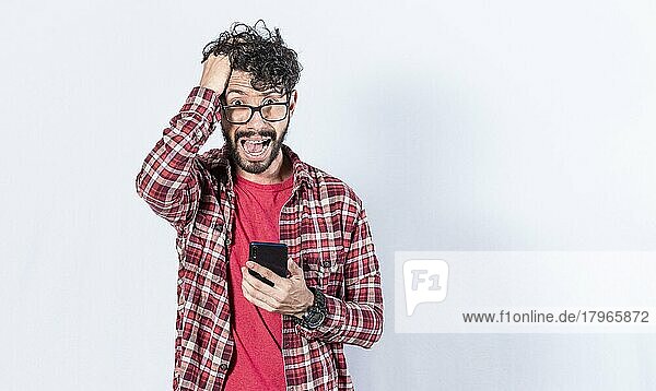 Besorgter junger Mann mit seinem Telefon in der Hand  Konzept eines Mannes  der mit seinem Handy betäubt wird