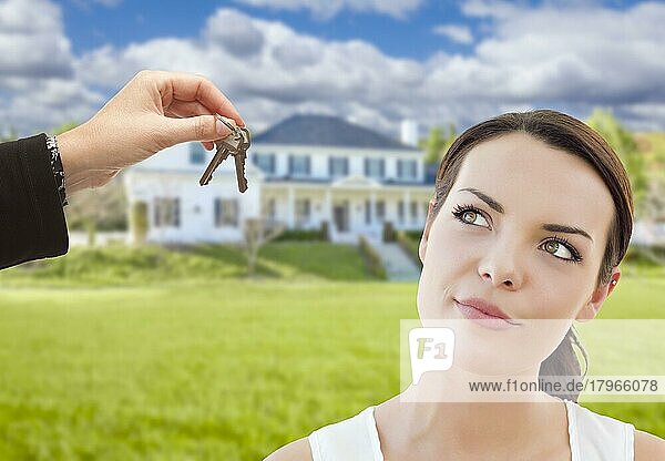 Immobilienmakler übergibt nachdenklicher hübscher gemischtrassiger Frau die Schlüssel vor dem Haus