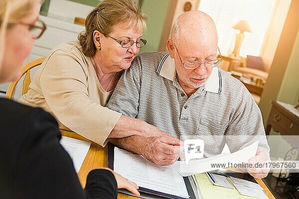 Senior adult couple going over documents in their home with agent at signing