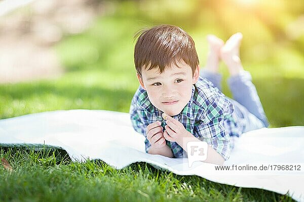 mixed-race chinese and caucasian young boy relaxing outside on the graß