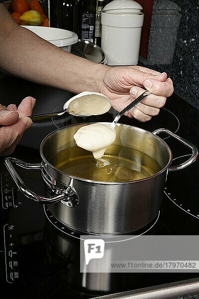 Schwäbische Küche  Versoffene Jungfern  Süßspeise  Zubereitung von Fettgebackenem  heißes Öl in einem Topf  Teig ausbacken  Männerhände  Löffel  Deutschland  Europa