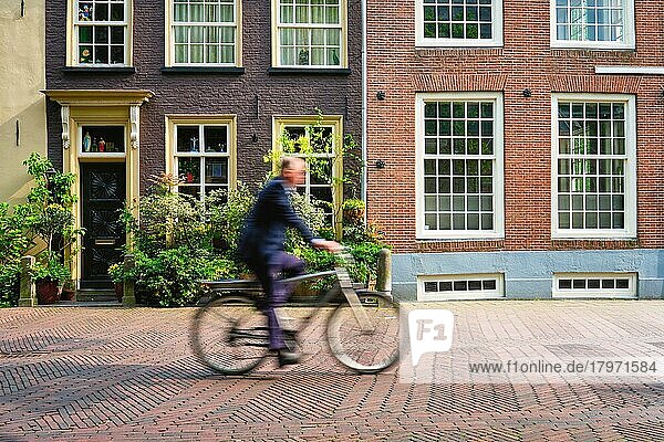 Bewegung unscharf Fahrradfahrer  Radfahrer Mann auf Fahrrad  sehr beliebtes Transportmittel in den Niederlanden in Straße mit alten Häusern von Delft  Niederlande  Europa